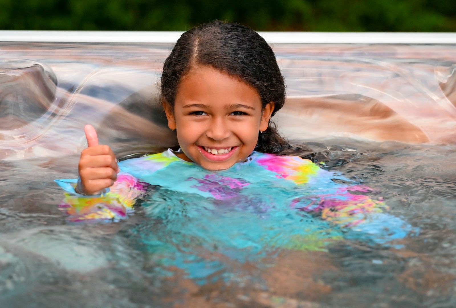 A child enjoying a Garden Leisure hot tub, giving a thumbs up